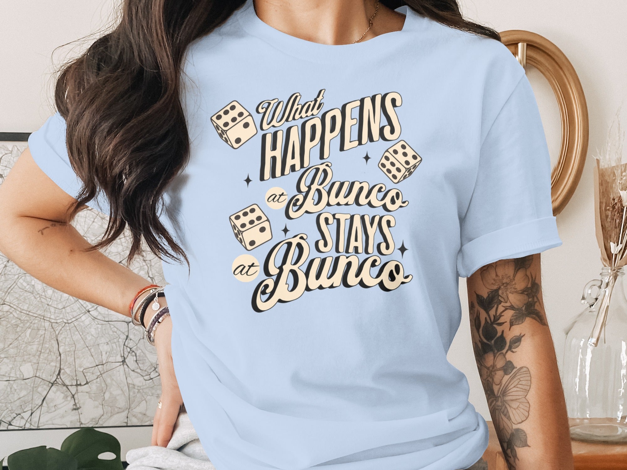 Light blue t-shirt with dice graphic and text "What Happens at Bunco Stays at Bunco".
