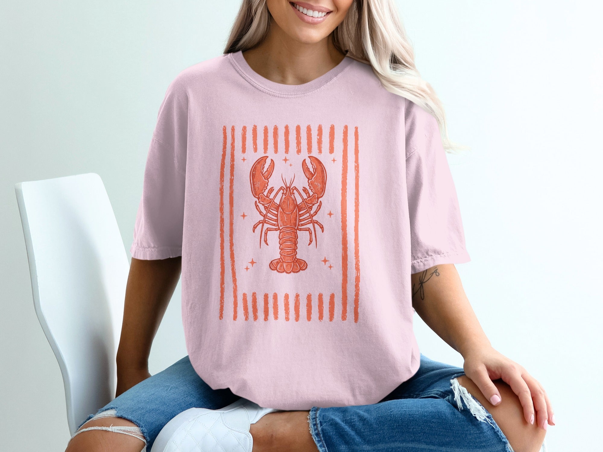 Pink t-shirt with a stylized orange lobster graphic and vertical stripes.