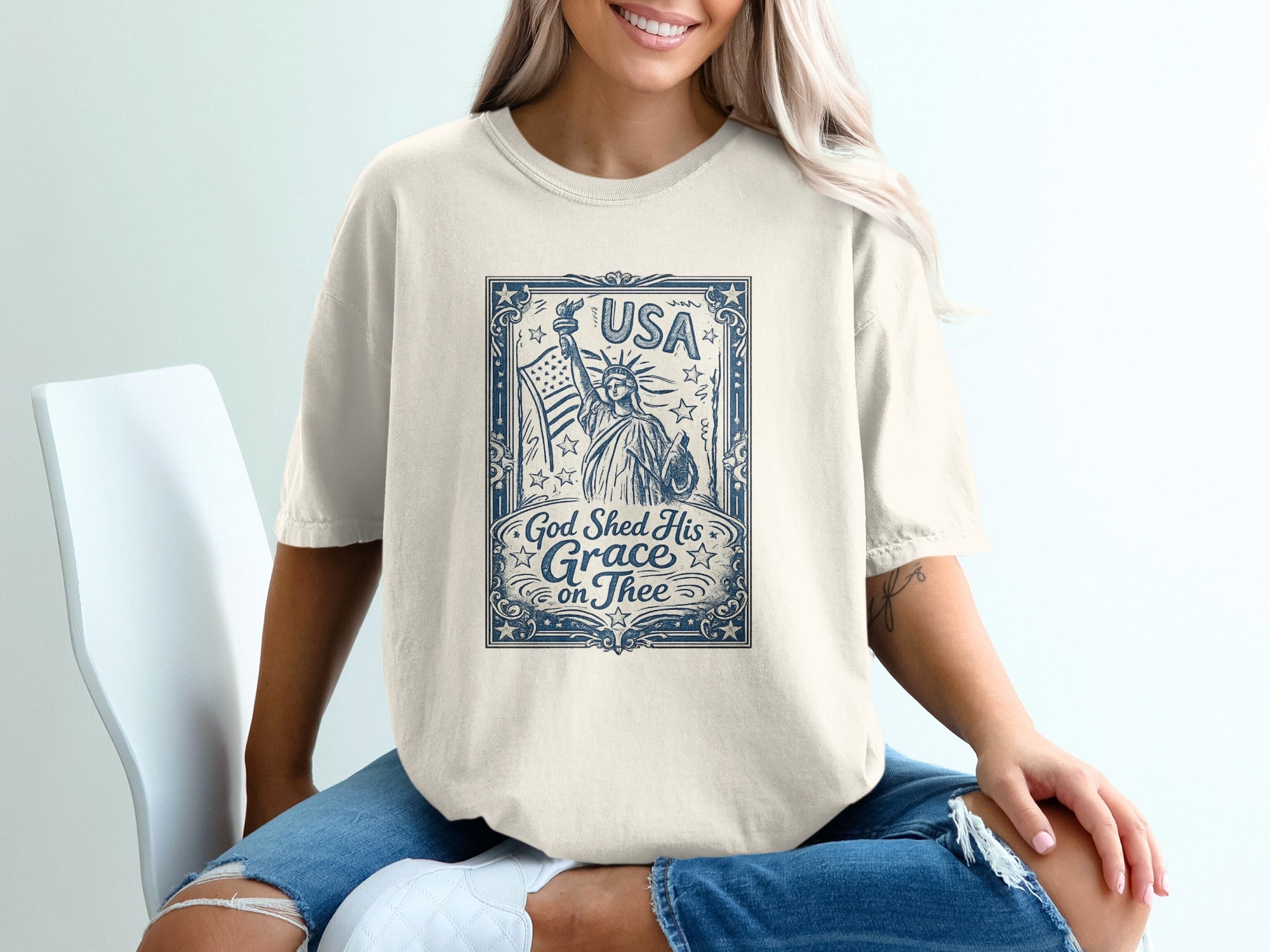 Cream t-shirt featuring Statue of Liberty and "USA God Shed His Grace on Thee" text.
