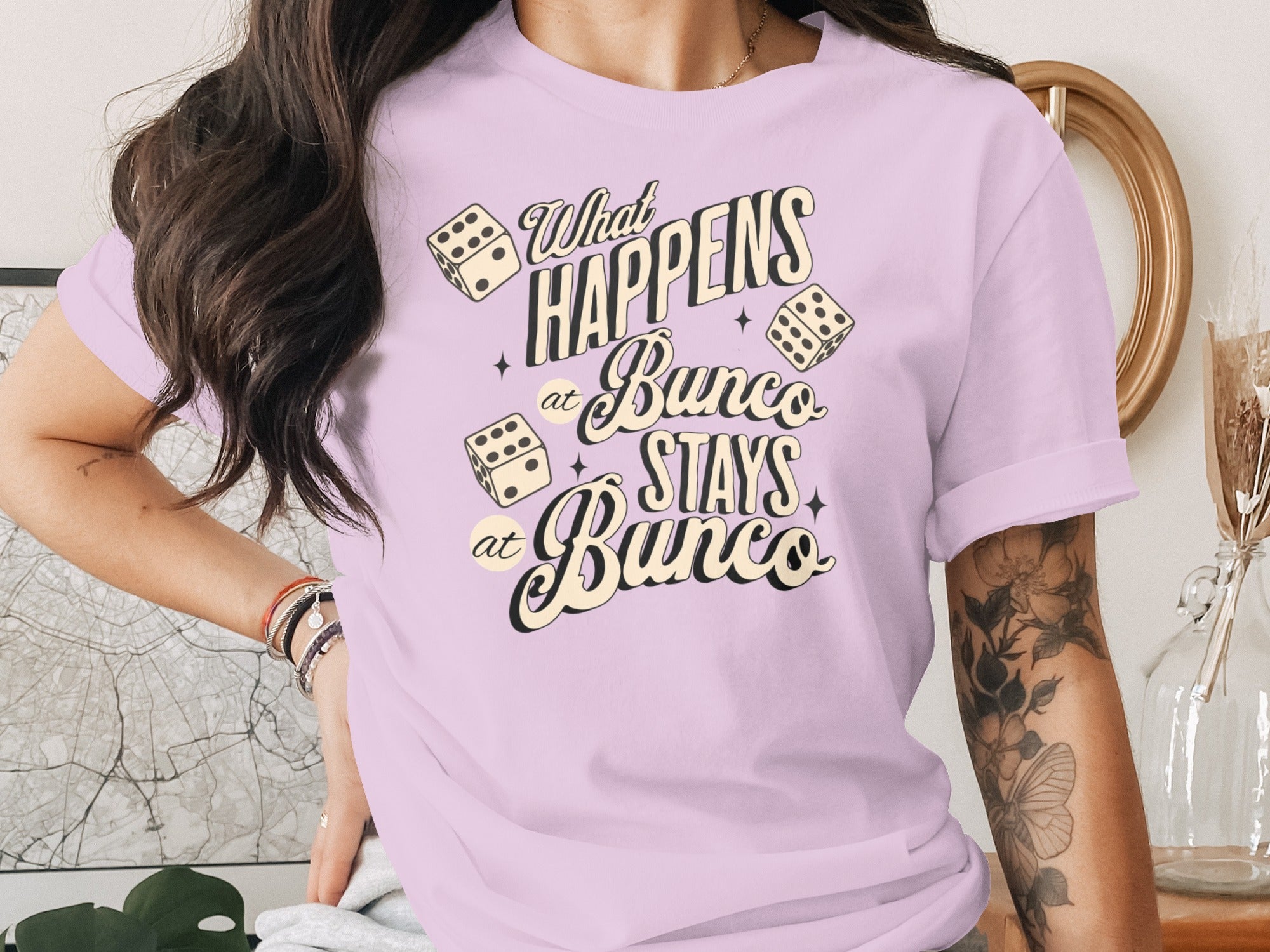 Bunco dice graphic on a lavender t-shirt reads "What happens at Bunco stays at Bunco".