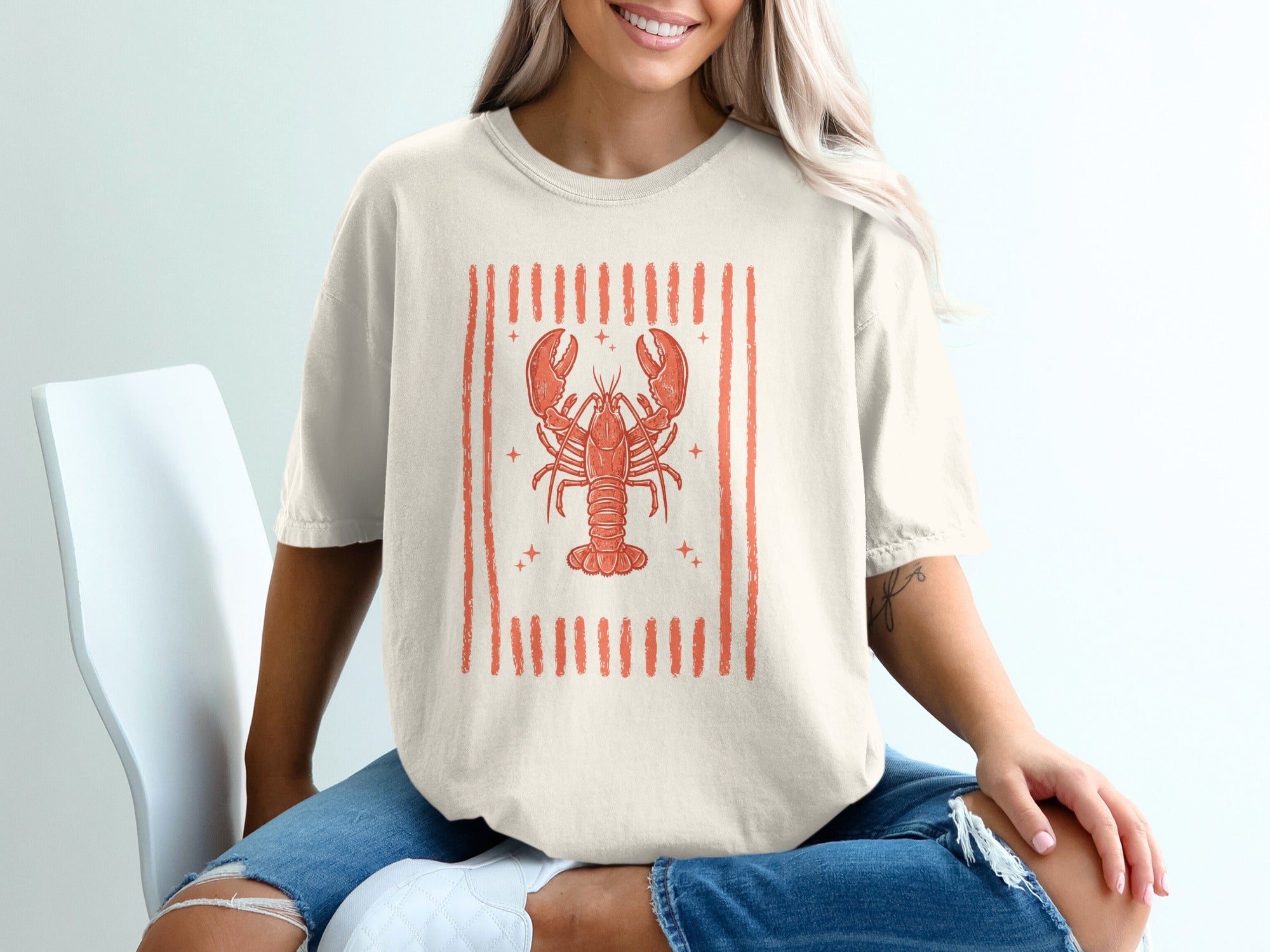 Cream t-shirt with an orange cartoon lobster graphic and vertical stripes.