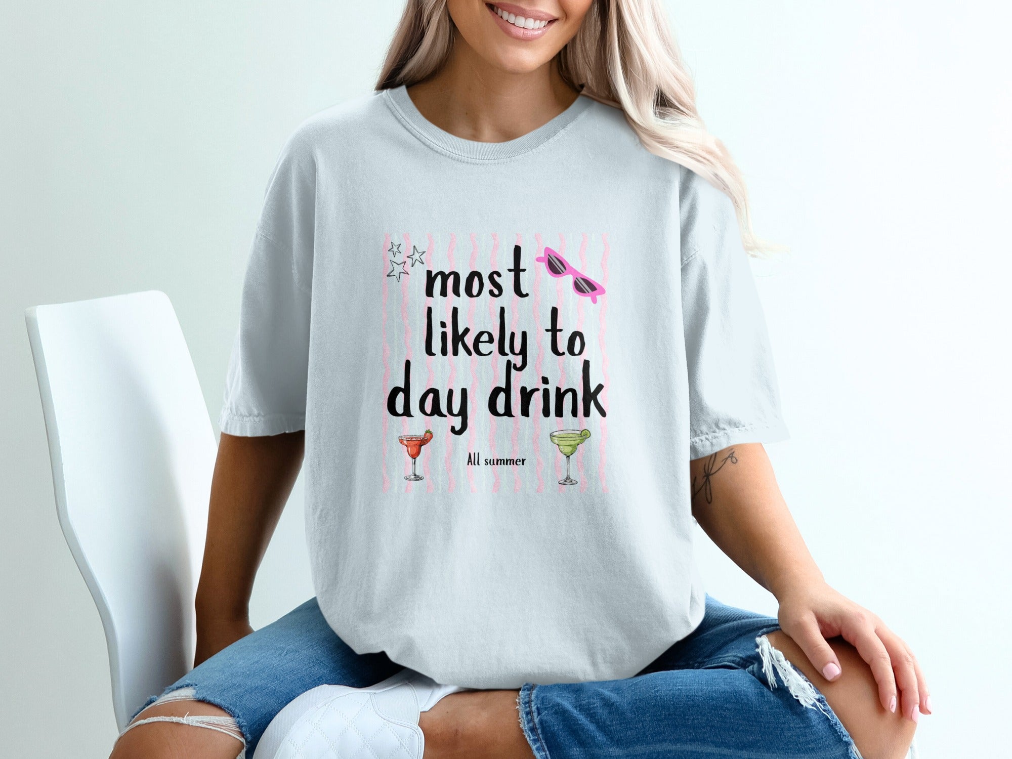 Light blue t-shirt with "Most likely to day drink" text, pink stripes, sunglasses and cocktail graphics.