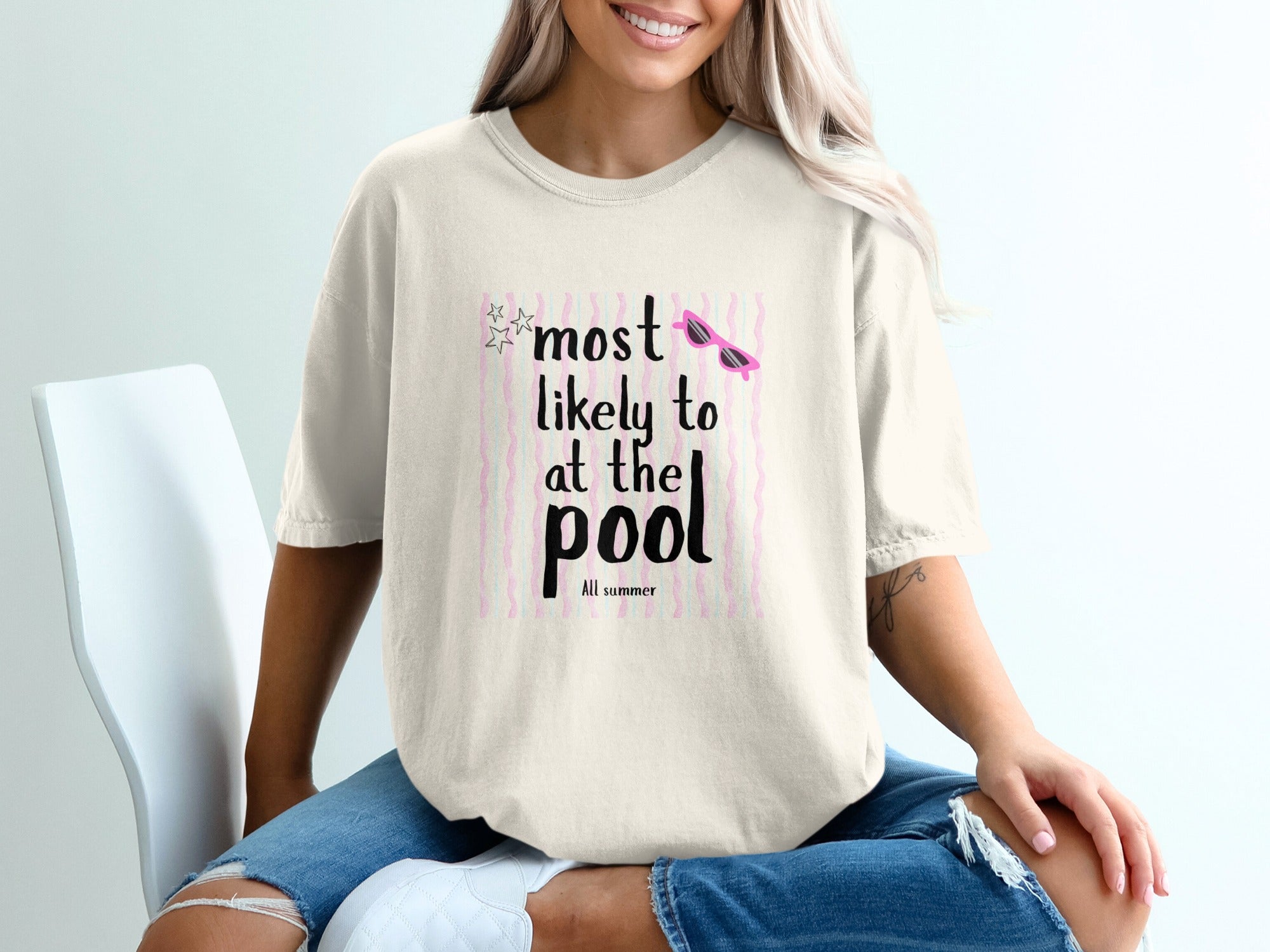 Cream t-shirt with "most likely to at the pool" text and sunglasses graphic.