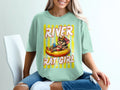Mint t-shirt with illustration of a rat wearing sunglasses in an inner tube, text "River Rat Girl."