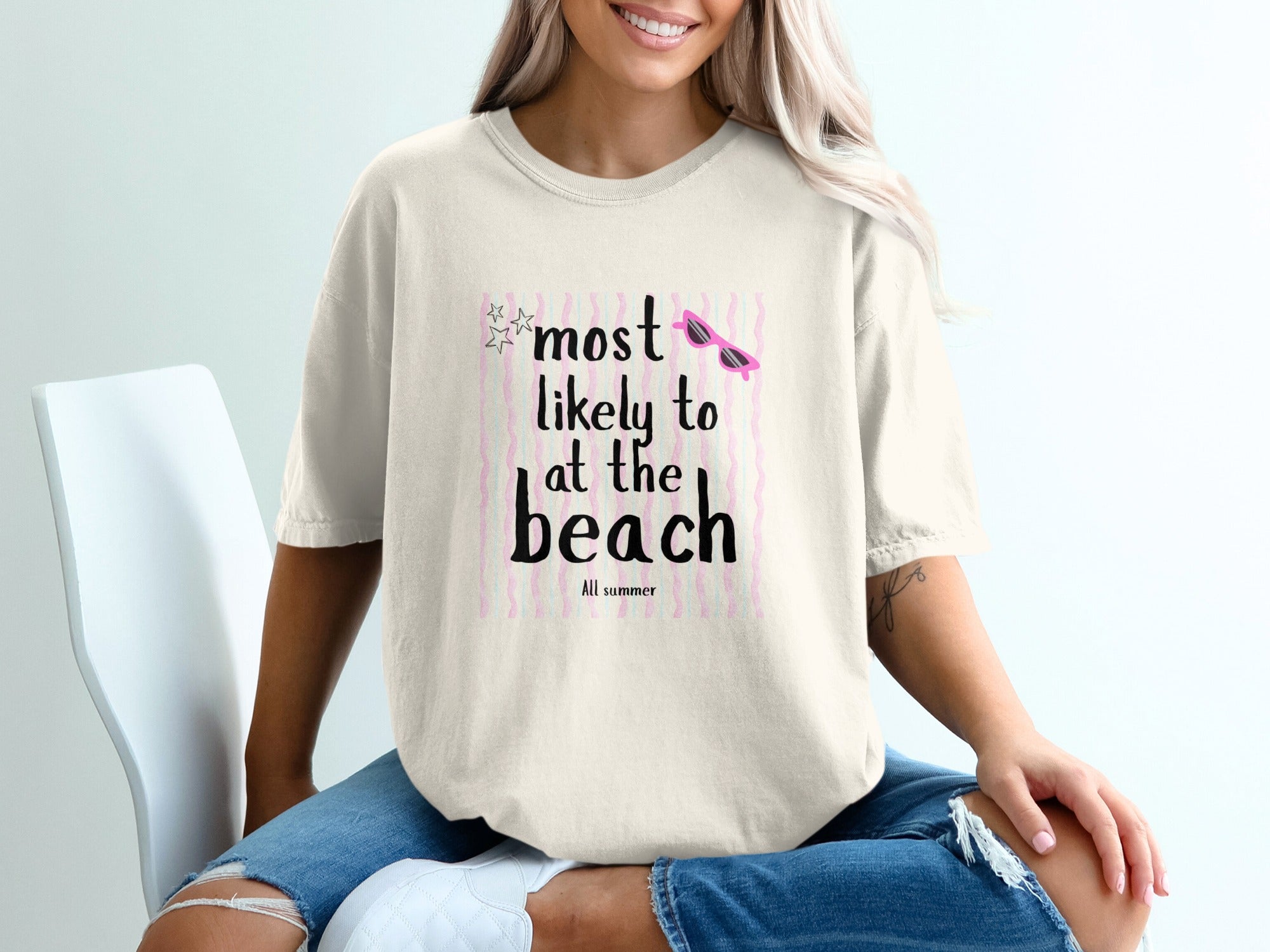 Ecru t-shirt with "Most Likely to at the Beach All Summer" text and sunglasses graphic.
