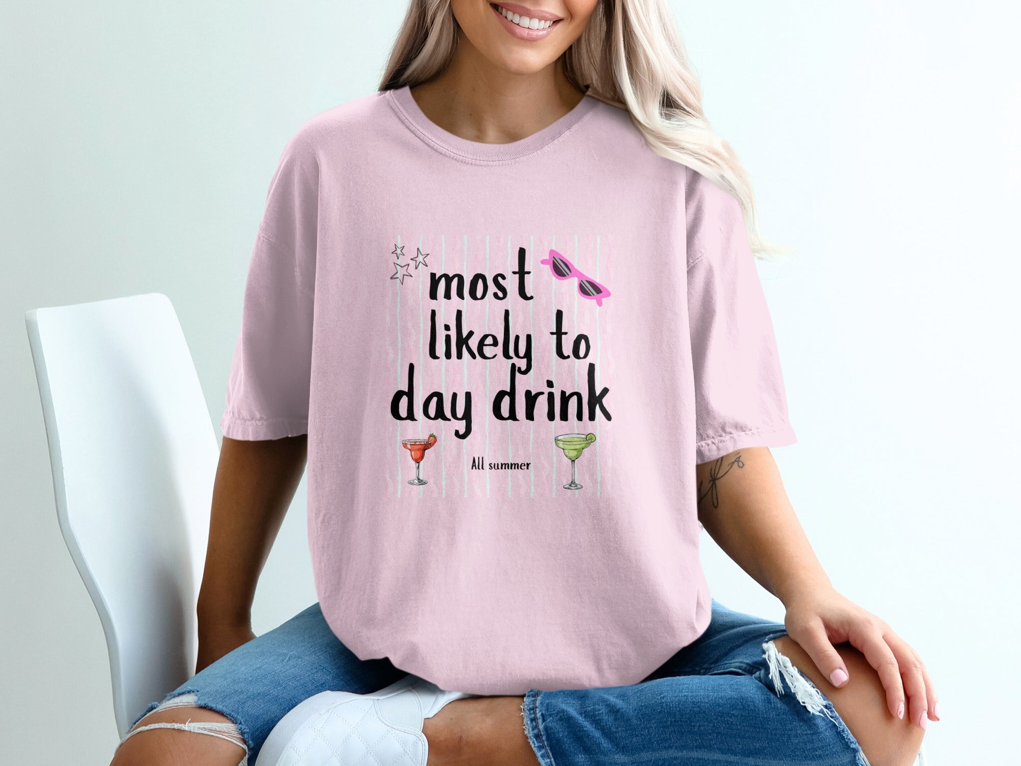 Pink t-shirt with black text "most likely to day drink" and summer graphics.