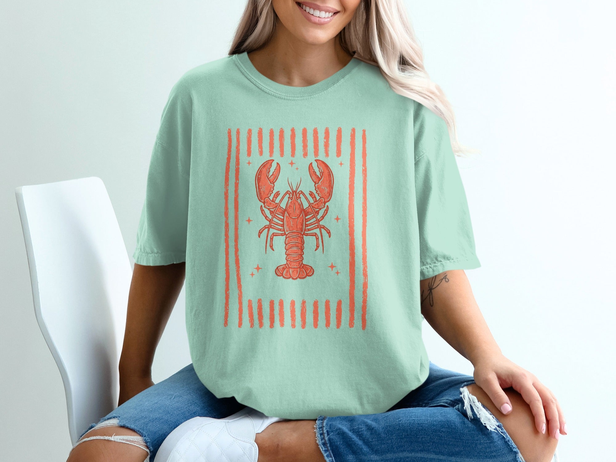 Mint green t-shirt featuring an orange lobster graphic with striped border.